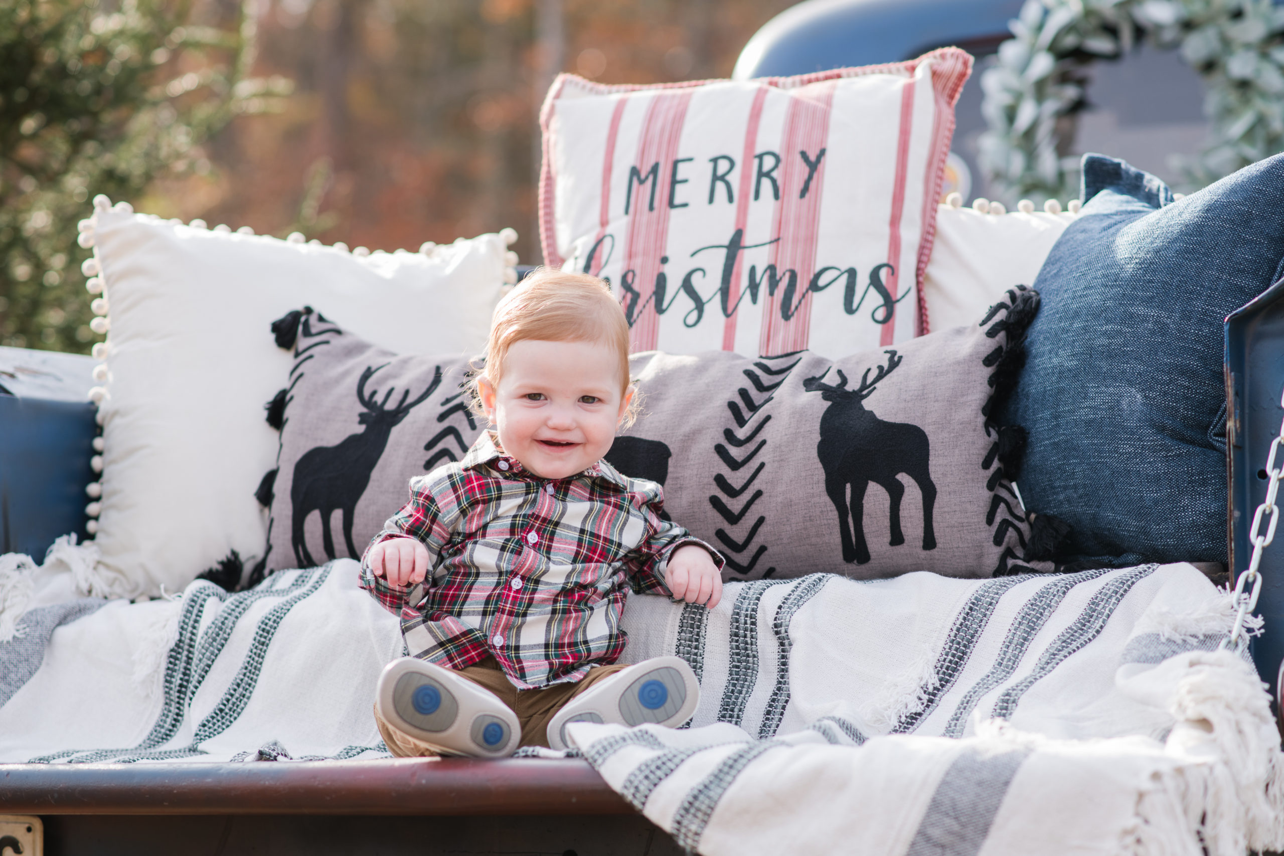 baby on blue truck with christmas pillows