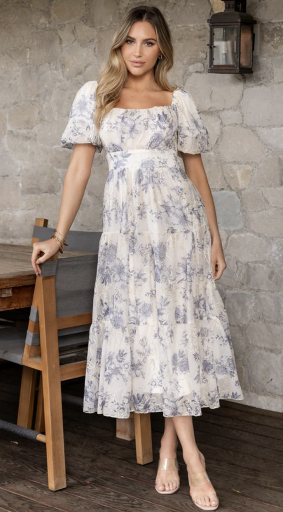 Cream and soft blue floral print tiered maxi dress with short puff sleeves and a fitted bodice – an elegant choice for golden hour photography.