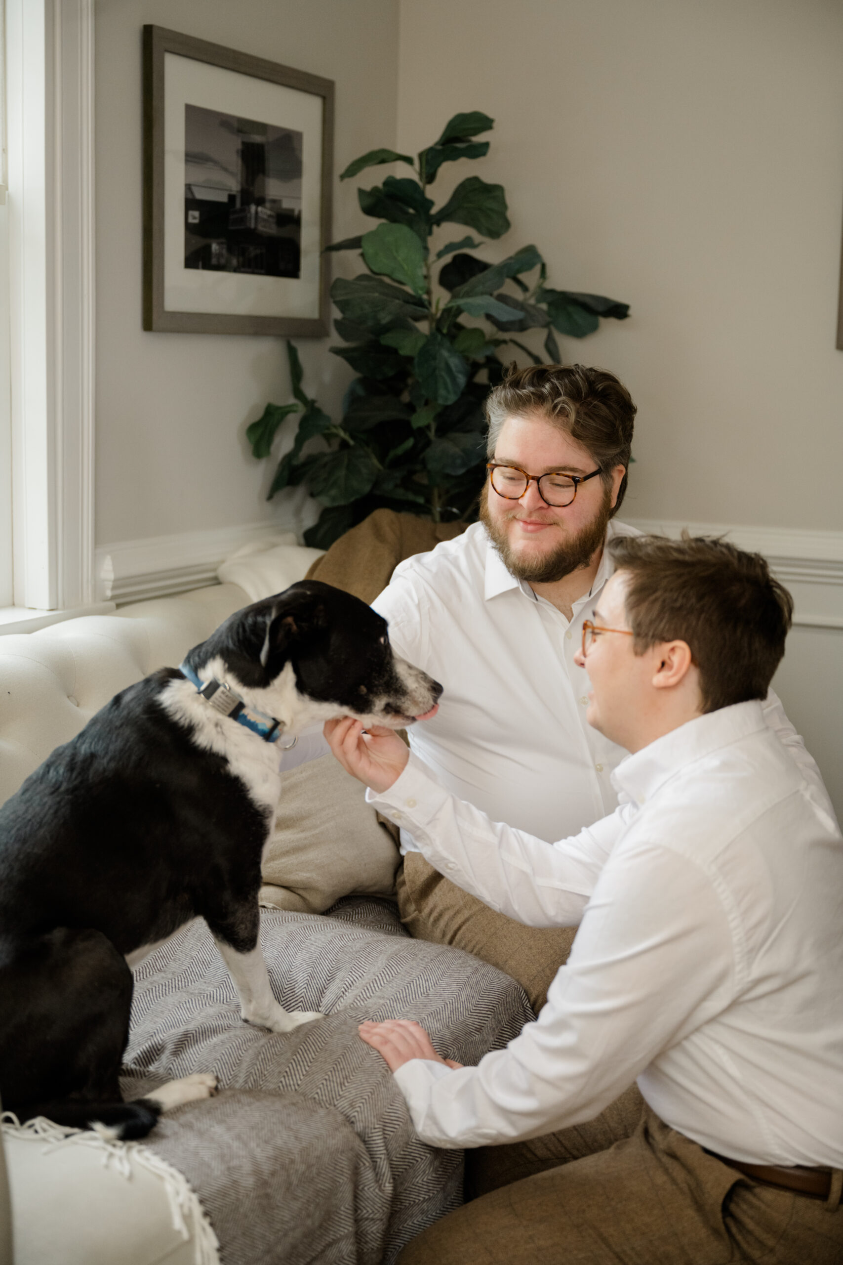 Sweet moment of the two grooms petting their black and white dog Marlo while getting ready before their wedding.