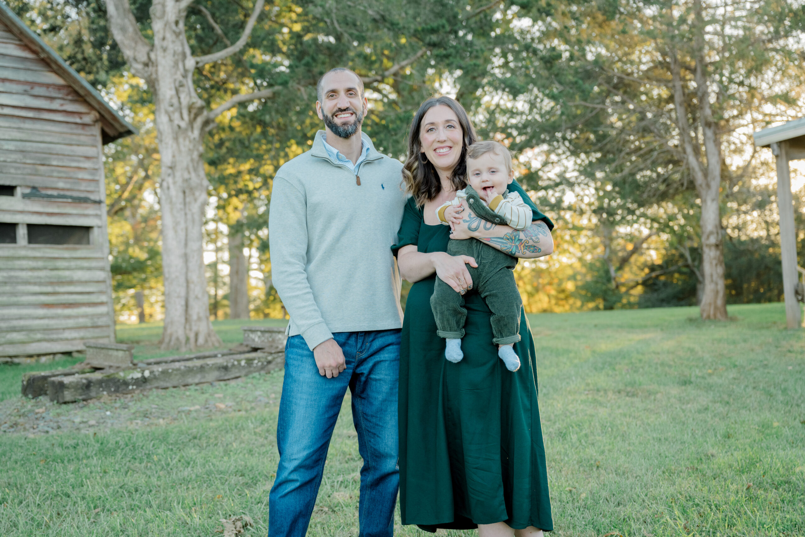 Mom and dad hold their baby boy close as they pose during golden hour at Pleasant Grove Park in Fluvanna, part of a joyful family photo session.