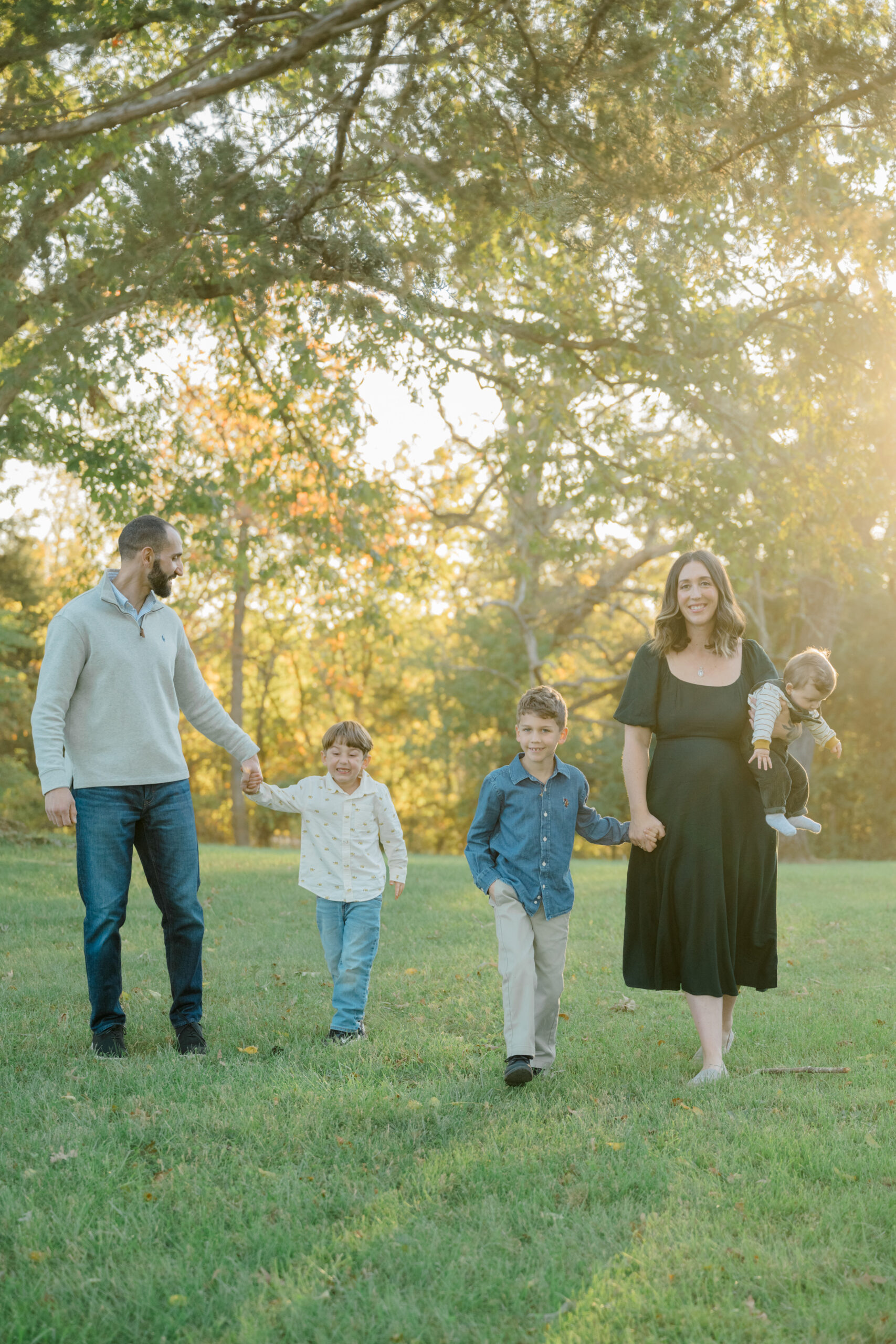 Sacco family of five walks hand-in-hand through golden hour light at Pleasant Grove Park in Fluvanna, Virginia during their fall photo session.