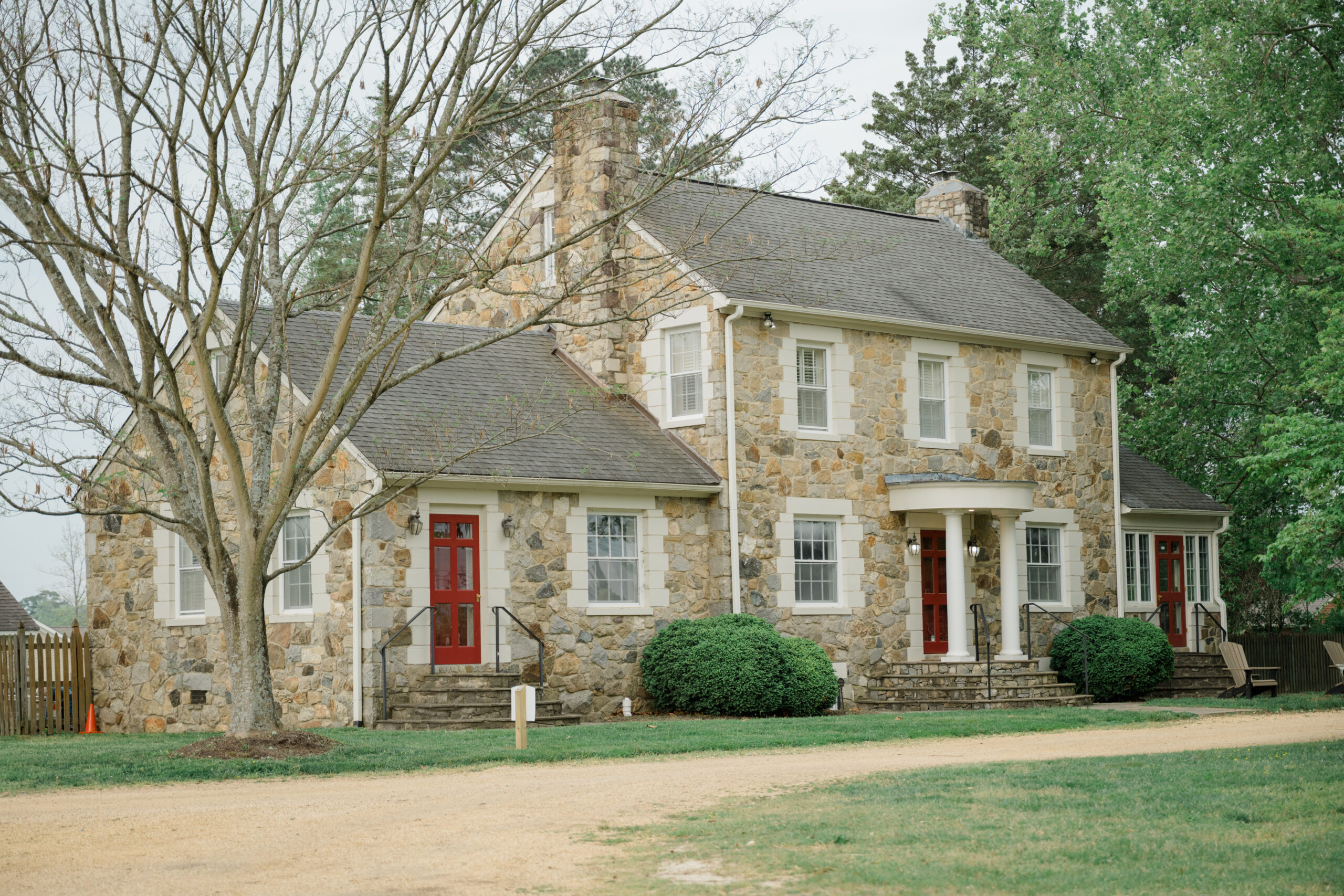 Exterior view of a stone house with red doors and white trim at Woodside Farms, used as a getting ready location for the wedding.