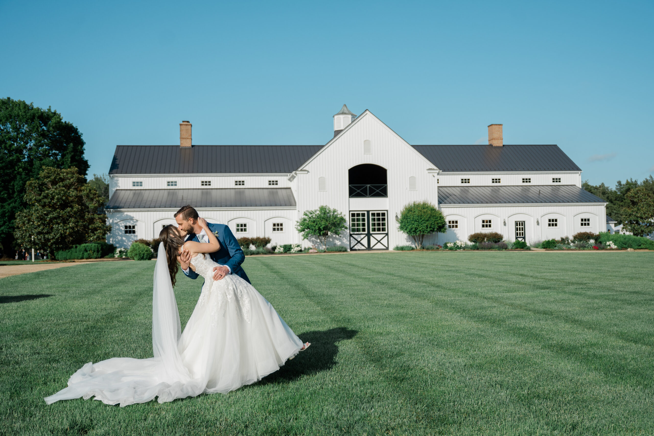 Bride and groom kissing at sunset in vineyard with Blue Ridge Mountains in background at a Charlottesville wedding venue