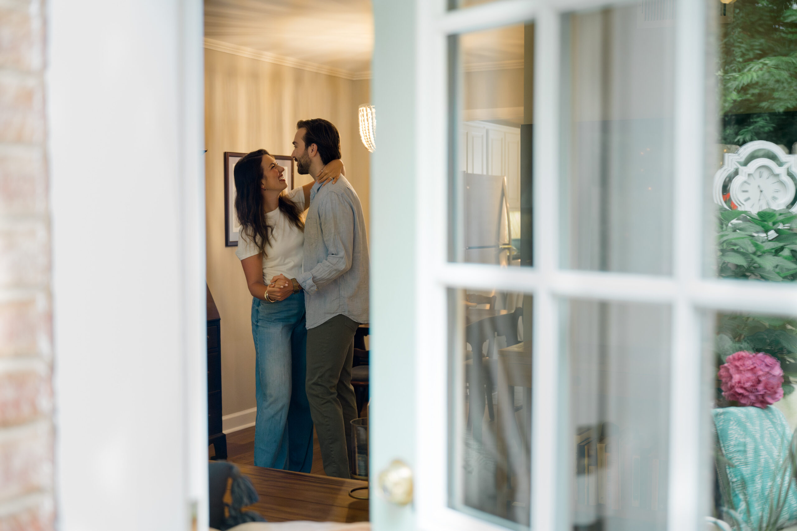 Couple slow dancing in their Charlotte, NC living room during an emotional farewell photo session, captured through the front door window.