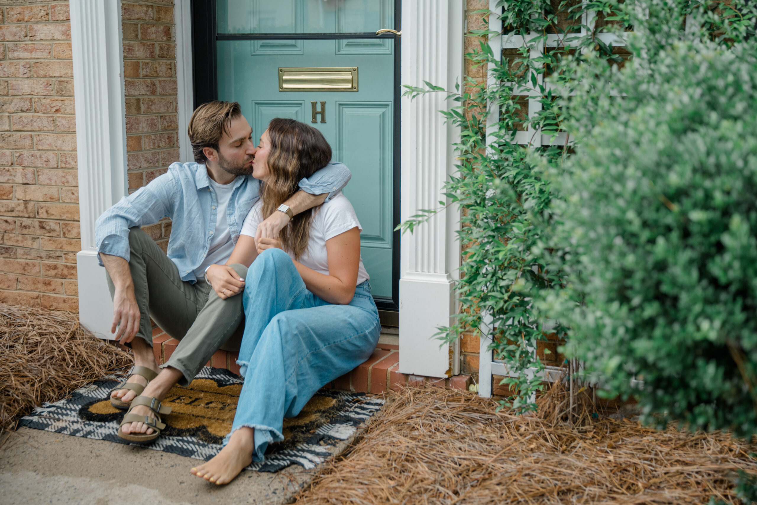 Newlywed couple sharing a kiss on the front porch of their first home in Charlotte, NC during an intimate farewell photo session.