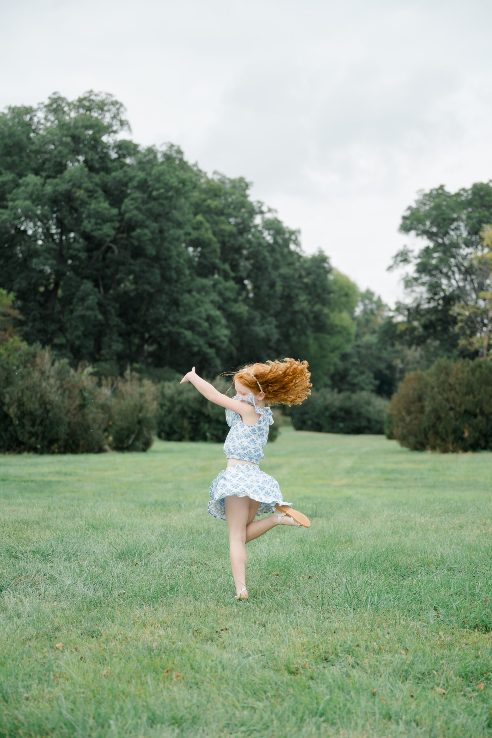 Little girl twirling in the open field at Barboursville Vineyards during a family session.