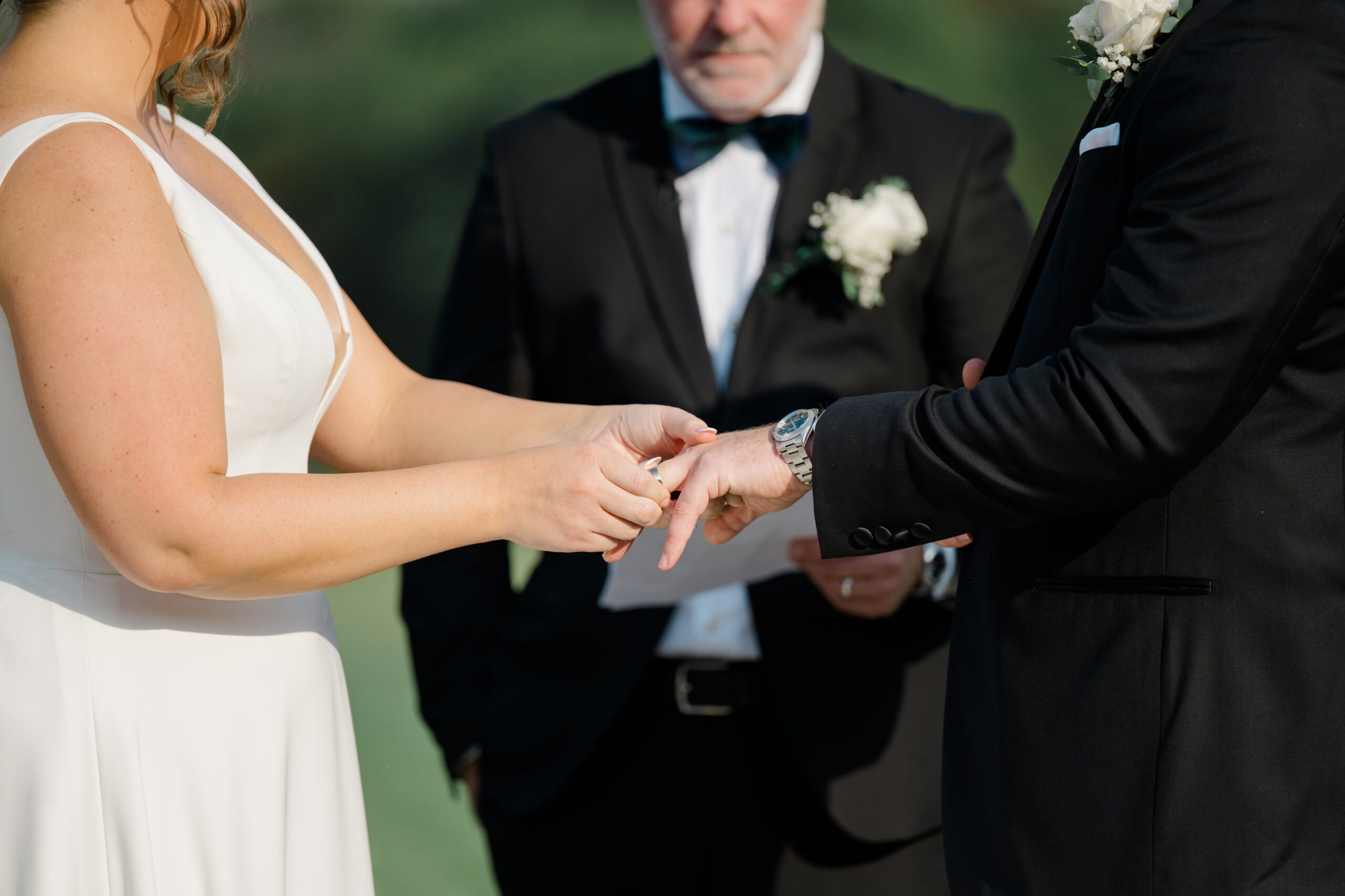 Bride placing a wedding ring on the groom’s finger during an emotional black tie ceremony at Gordon Springs