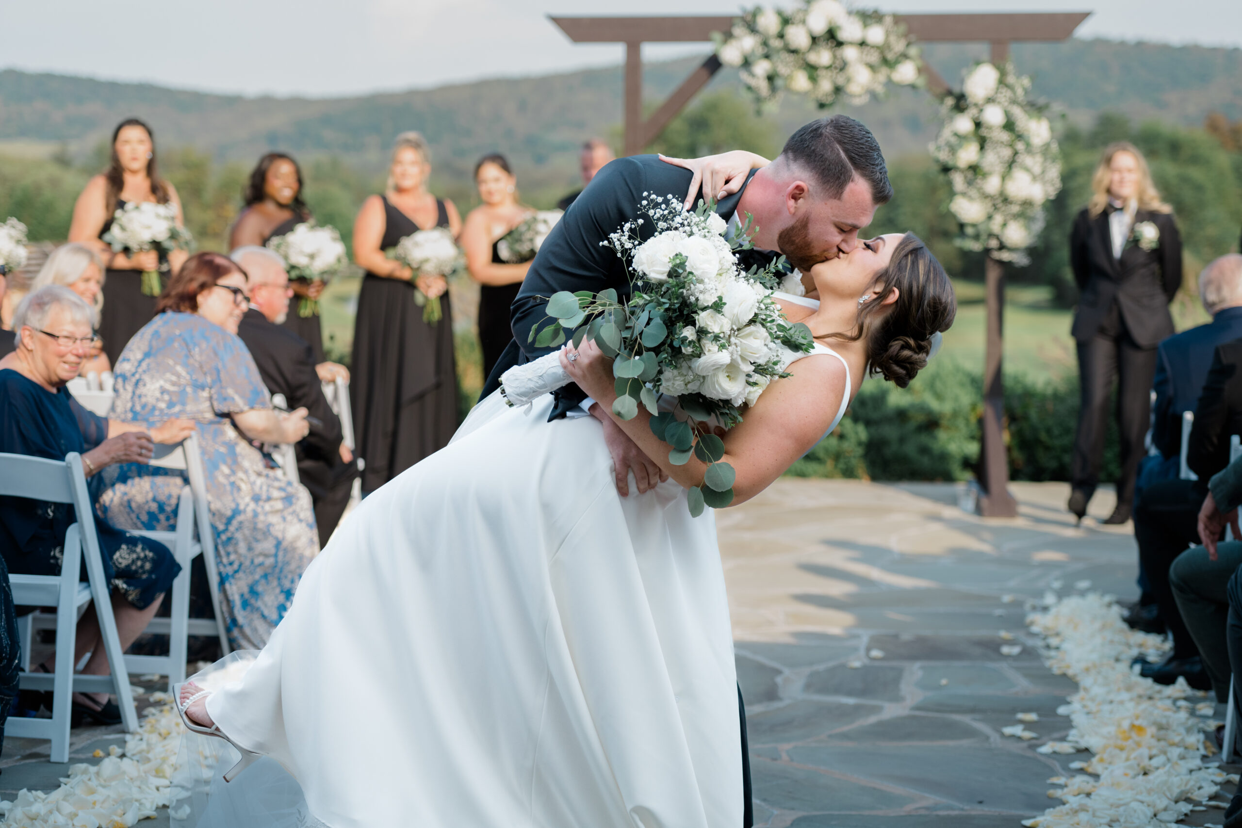 Bride and groom sharing their first kiss during an outdoor black tie ceremony with mountain views at Gordon Springs