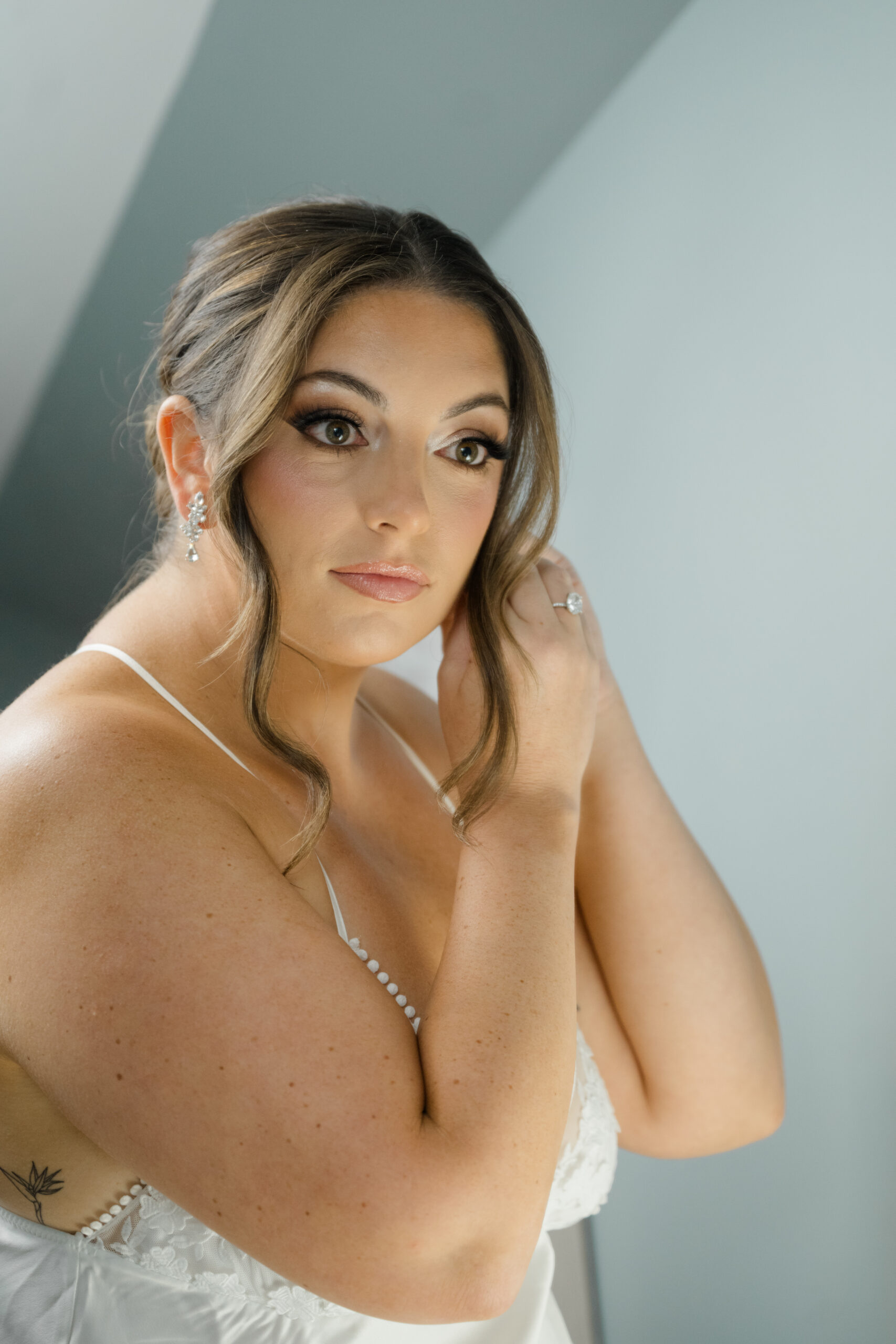 Bride adjusting her earrings during a quiet getting ready moment before the ceremony