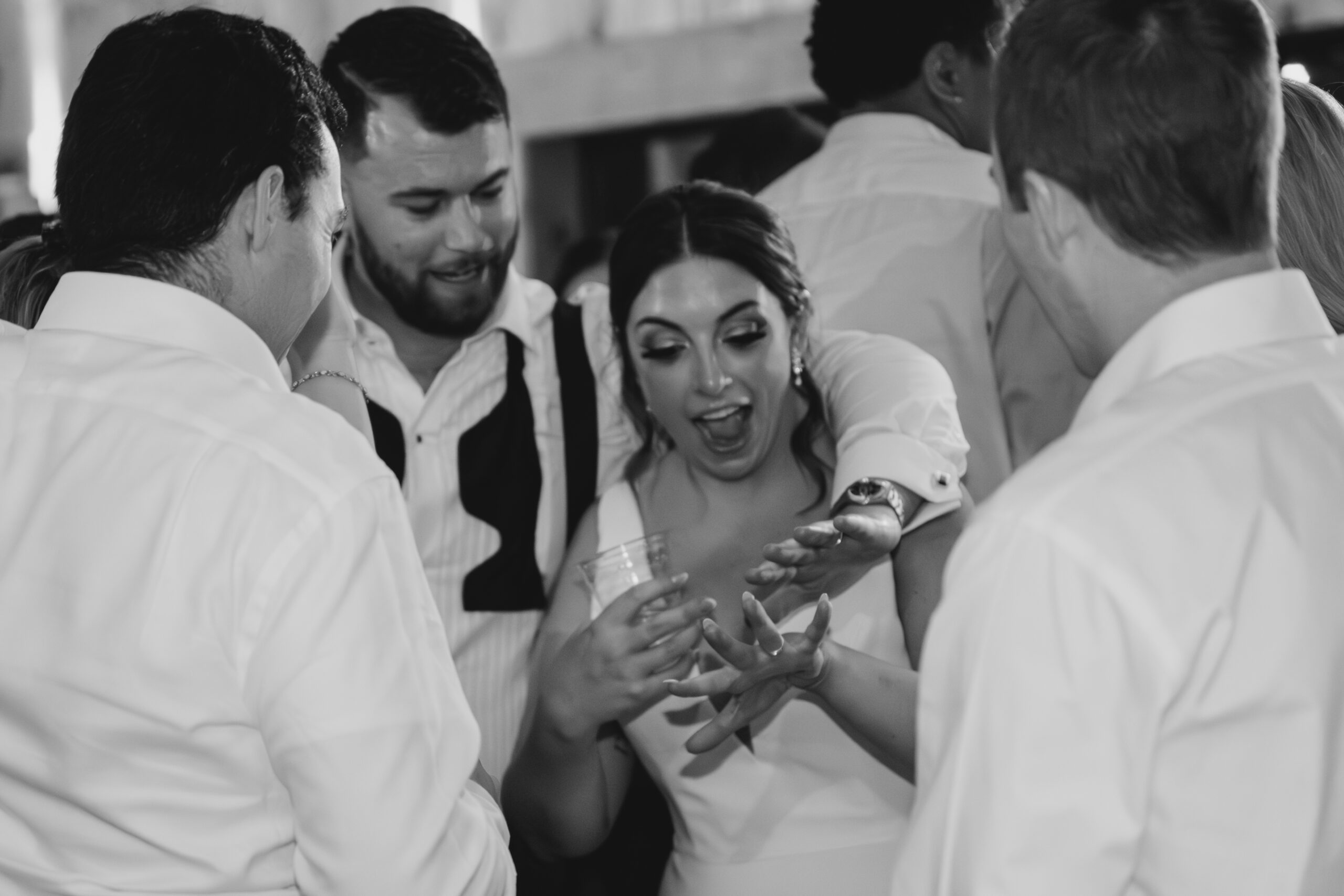 Bride laughing with friends on the dance floor during a joyful black tie wedding reception