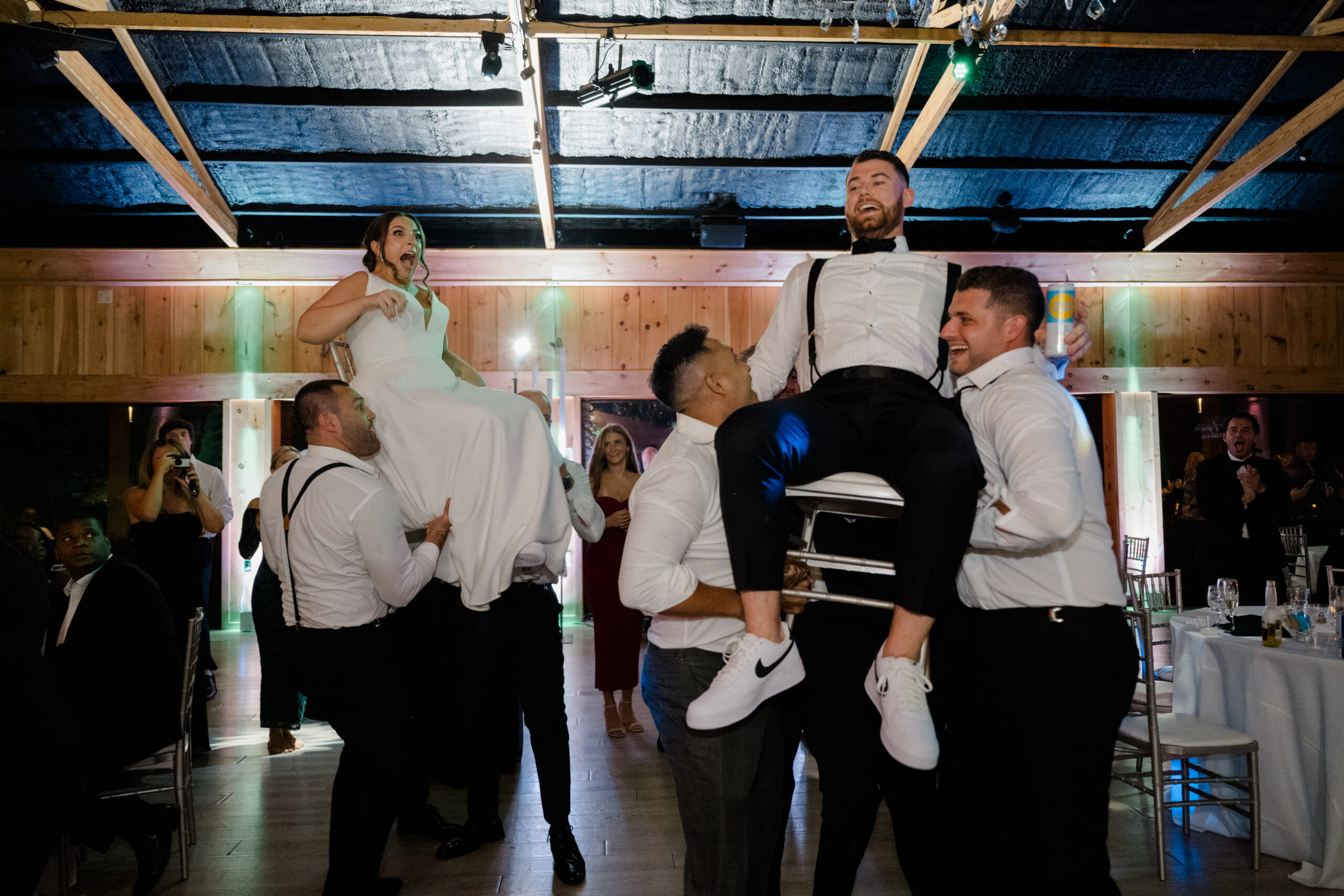 Bride and groom lifted into the air by friends during a high-energy wedding reception celebration