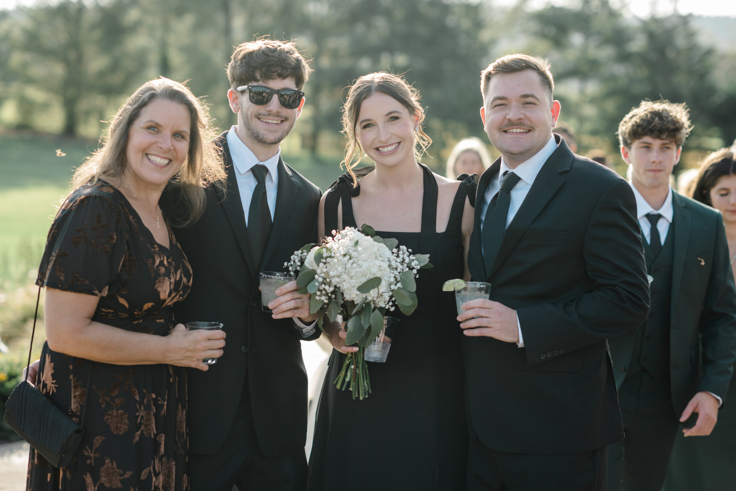 Wedding guests smiling and posing together during cocktail hour at a black tie wedding celebration