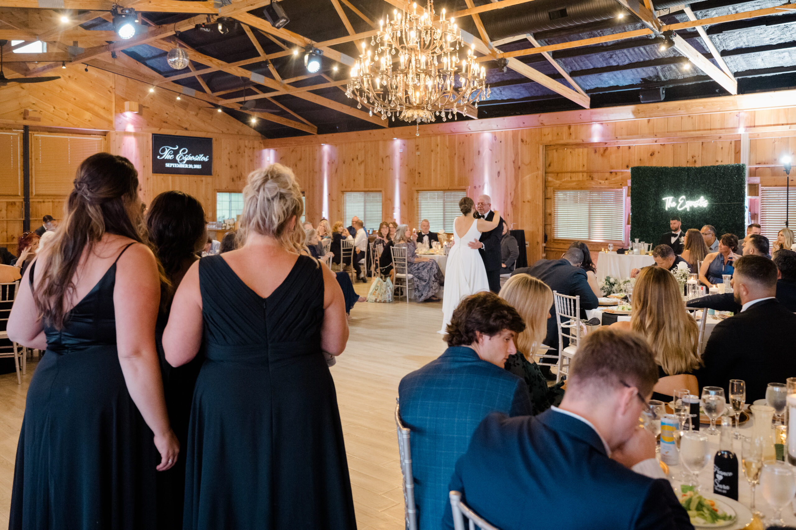 Bride dancing with a parent during an emotional moment at the wedding reception surrounded by guests