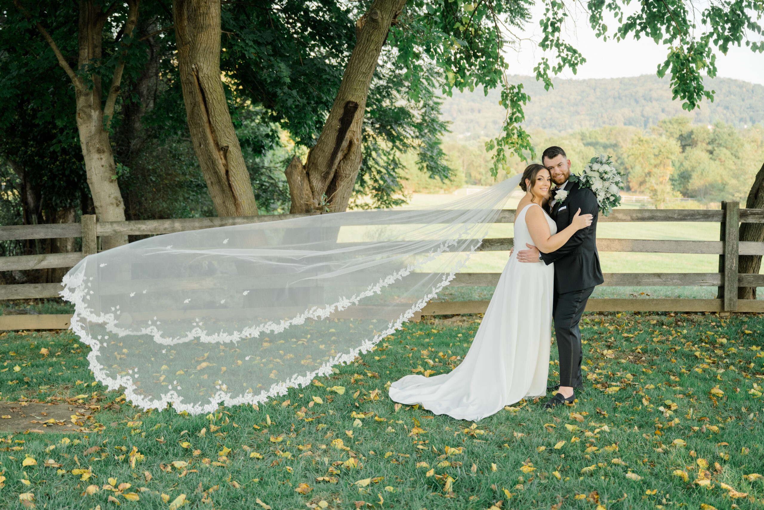 Bride and groom embracing during intimate portraits with the bride’s cathedral veil flowing behind them at Gordon Springs