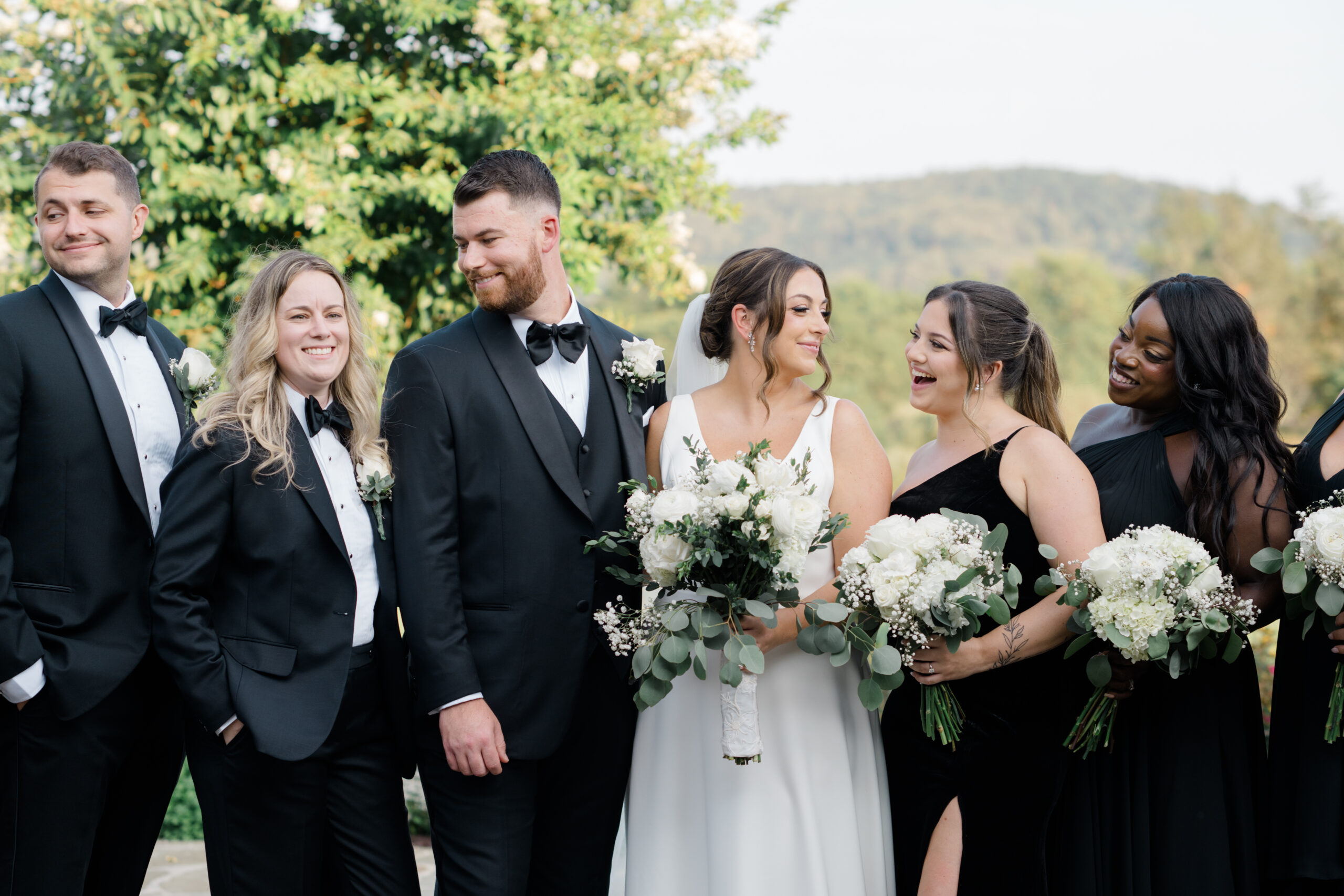 Bride and groom laughing with their wedding party during outdoor portraits with mountain views at Gordon Springs