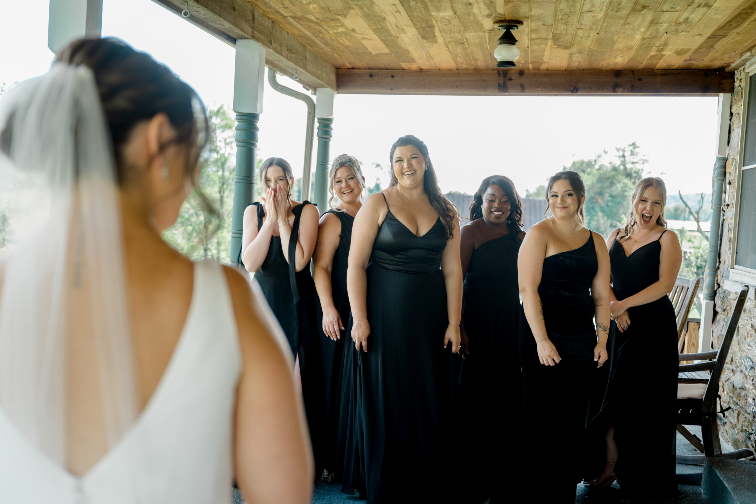 Bride revealing her wedding look to her bridesmaids during an emotional first look moment