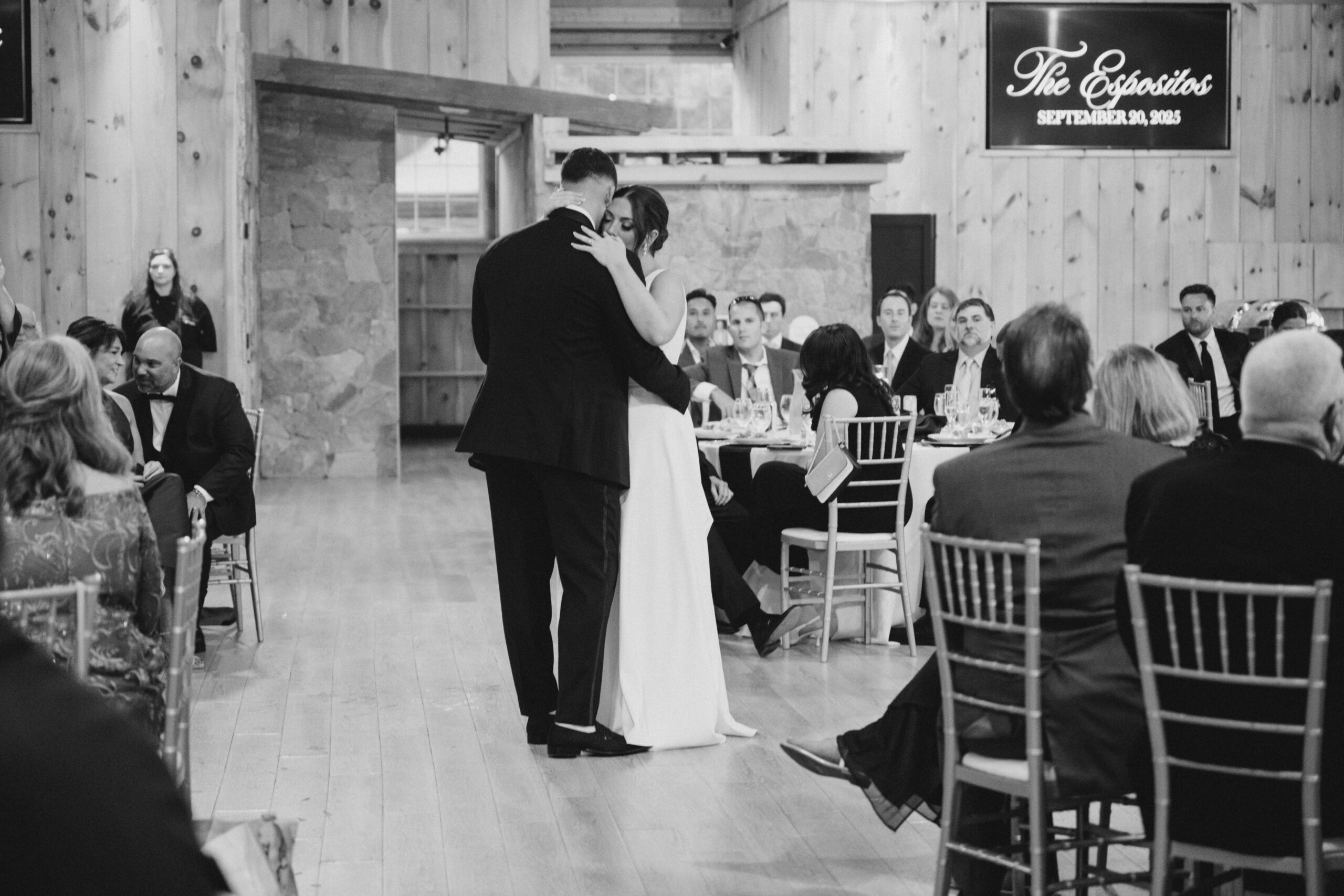 Bride and groom sharing their first dance surrounded by seated guests during the wedding reception