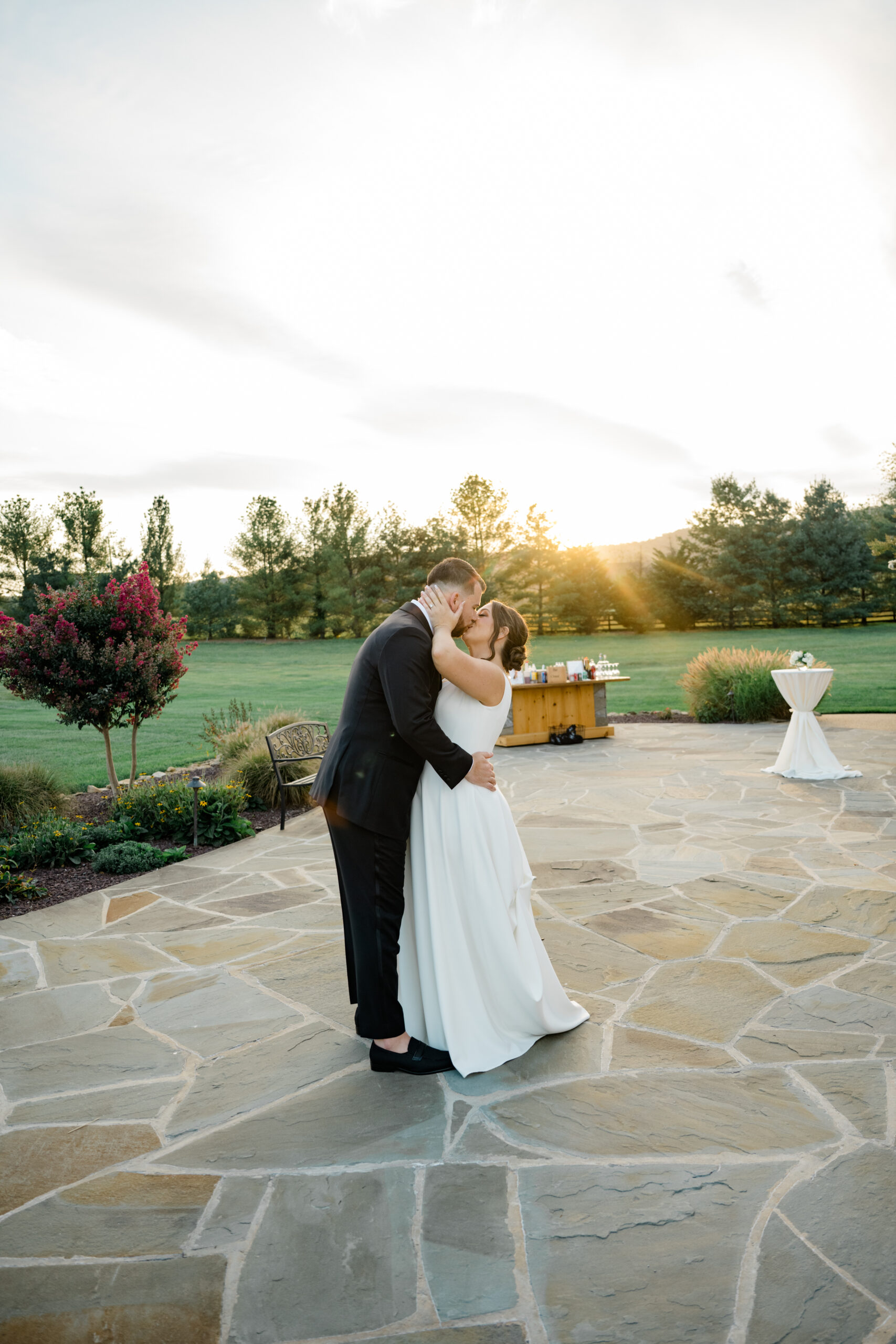 Bride and groom sharing a quiet kiss during golden hour portraits on the stone patio at Gordon Springs