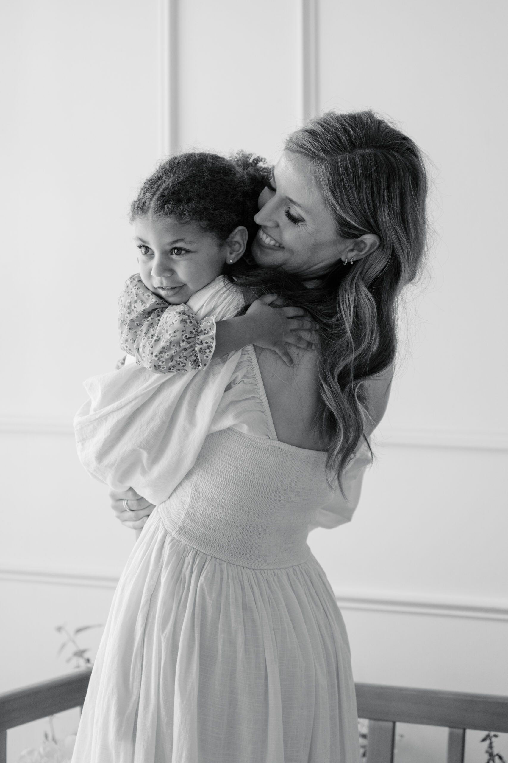 Motherhood photography membership portrait of a mother holding her toddler in a black and white studio session.